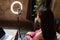 Young woman making photo or video content for social media with smartphone and light of ring lamp. Beauty blogger smiles