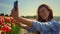 Young woman making selfie in beautiful flower garden. Girl smiling in smartphone