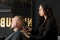 young woman male master hairdresser makes a man\\\'s hair with a razor in a barbershop