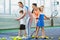 Young woman and man or coach teaching children how to play tennis on a court indoor