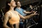 Young woman and man on elliptical stepper trainer exercising in gym