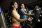 Young woman and man on elliptical stepper trainer exercising in gym