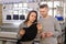 young woman and man looking at a knitted piece of clothes and discussing near a industrial knitting machine with black cones on i