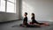 Young woman and man practicing yoga, doing Single Pigeon, Eka Pada Raja Kapotasana exercise, One Legged King Pigeon pose.