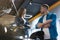 Young woman manager in business suit consulting young man customer standing near open bonnet in electric car dealership center,