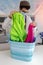 Young woman with mask and cap selecting colored laundry from baskets placed on a table in a commercial laundry washer and dryer