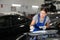 Young woman mechanic repairing car with putty and spatula