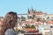 Young woman with medical face mask on Charles Bridge in Prague, Czech Republic. Blurred old town and Prague Castle in background.