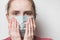 Young woman in medical mask against white background. Female is concerned about her health. Epidemic of Coronavirus