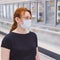 Young woman in medical mask chooses products in the refrigerator of the store