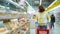 Young woman in medical mask choosing fresh bakery in supermarket