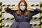 A young woman in a medical mask and gloves on the background of the restrictive fence, concept. Quarantine and isolation of people