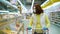 Young woman in medical mask and gloves by shelves with fresh pastry at store