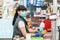 A young woman in a medical mask and gloves, working at the checkout in a supermarket. Concept of coronovirus, protection from
