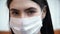 Young woman in medical mask looks into the camera; protection against coronavirus COVID-19