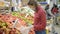 Young woman in medical mask and protective gloves picks apples in a supermarket. Coronavirus pandemic protection.