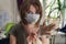 Young woman in medical mask puts protective gloves on hands at home