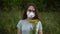 A young woman in a medical mask sniffs flowers and does not smell. Girl in glasses and a dress in nature.