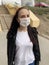 Young woman in medical mask on street. Adult female protecting yourself from diseases. Concept of threat of coronavirus