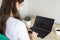 Young woman in medical mask working for laptop, portable computer from home on light background. Distance learning and work online