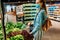 Young woman in a medical protective mask on her face buys vegetables and fruits in a supermarket. a young lady buys vegetables and