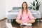 A young woman meditates while sitting next to a bed in . The girl does yoga exercises at home to relieve stress, taking