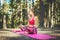 Young woman meditating in lotus position practicing yoga in a forest. Freedom concept. Relax, mind and body happiness