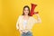 Young woman with megaphone on yellow background