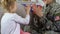 Young woman in military uniform playing with daughter at home, family time