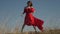 Young woman model in scarlet flowing in the wind dress and barefoot at sunset