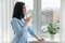 Young woman morning at home near the window drinking water with lemon, vitamin drink in winter spring season