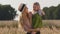 Young woman mother Caucasian mommy in hat stands in wheat field holding small girl daughter child kid talking with