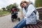 young woman mother of postpartum depression sits with built-in feelings in the park on a bench next to a baby stroller