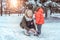 Young woman, mother puts on skis in winter in woods park, to the small son to boy of 3-6 years. Caring support, first