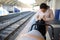 Young woman, mother searching clothes on the backpack while waiting to board the high speed electric train