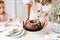 Young woman mother in white holding in hands Large round chocolate almond cake on the table with New Year serving, christmas white