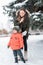 Young woman mother, in winter on street, walks with young son a boy of 3 years. Warm jacket winter clothing. Rest on the