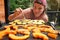 Young woman moving pieces of potato with fork, blurred pieces of orange butternut squash grilled on electric grill in foreground