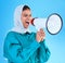 Young woman, muslim and megaphone in studio for protest, human rights and scream by blue background. Girl, islam and