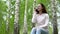 Young woman in nature with a phone. A girl sits on a stump in a birch forest and talks on the phone.