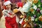 Young woman near Christmas tree and gift boxes eating hamburger