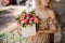 Young woman neatly holds in her hands white square box with flower arrangement