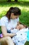 Young woman and new mother breastfeeding newborn baby outside in park, pretty mom holding infant in hands and nursing in public