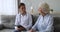 Young woman nurse writing in clipboard talking with senior patient