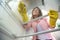 Young woman observed from the inside of a refrigerator doing some shelf cleaning