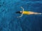 Young woman in a one-piece yellow swimsuit floats on the surface of the water.