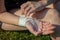 A young woman in the open air independently bandages a damaged wrist with a medical gauze bandage. Close-up