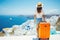 Young woman with orange suitcase traveling on Santorini island, Greece, Happy moment with young woman rear view tourist as orange