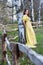 Young woman outdoors in historical yellow dress leaning on tree