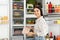 Young woman with pack of sausages near refrigerator